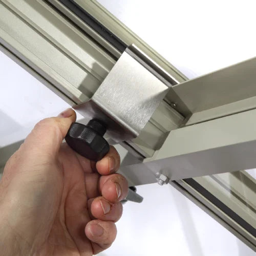 A hand tightens a black knob on a metallic frame, possibly part of a Rhino Greenhouse structure, with a white background.