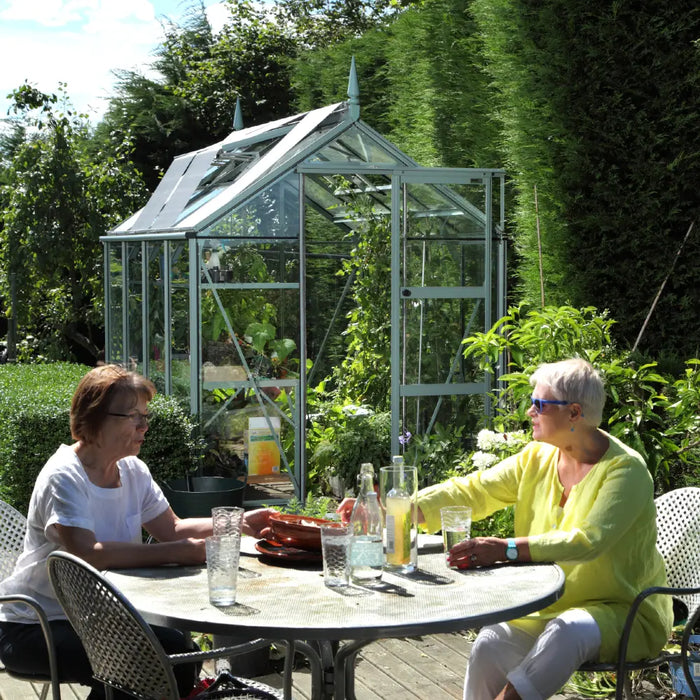 Two ladies enjoying a drink in front of their rhino greenhouse