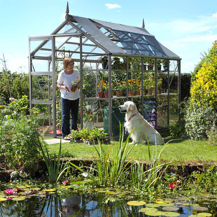 Lady and her dog outside her Rhino Greenhouse in a beautiful garden setting