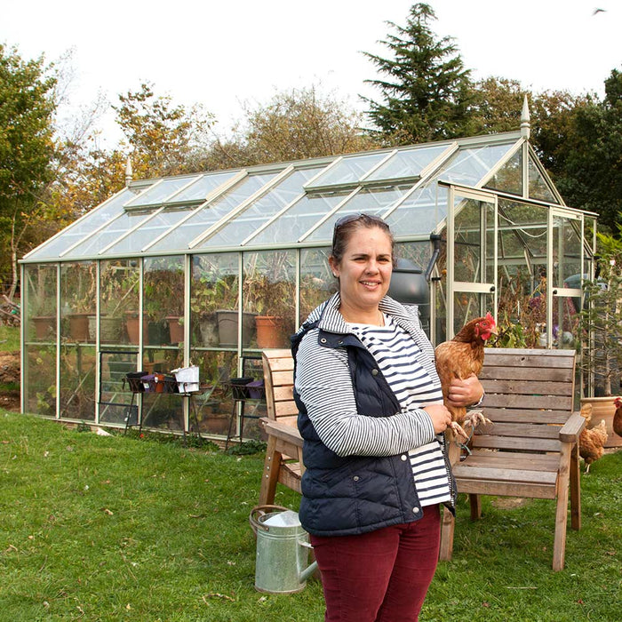 Woman holding a chicken infront of her Rhino greenhouse